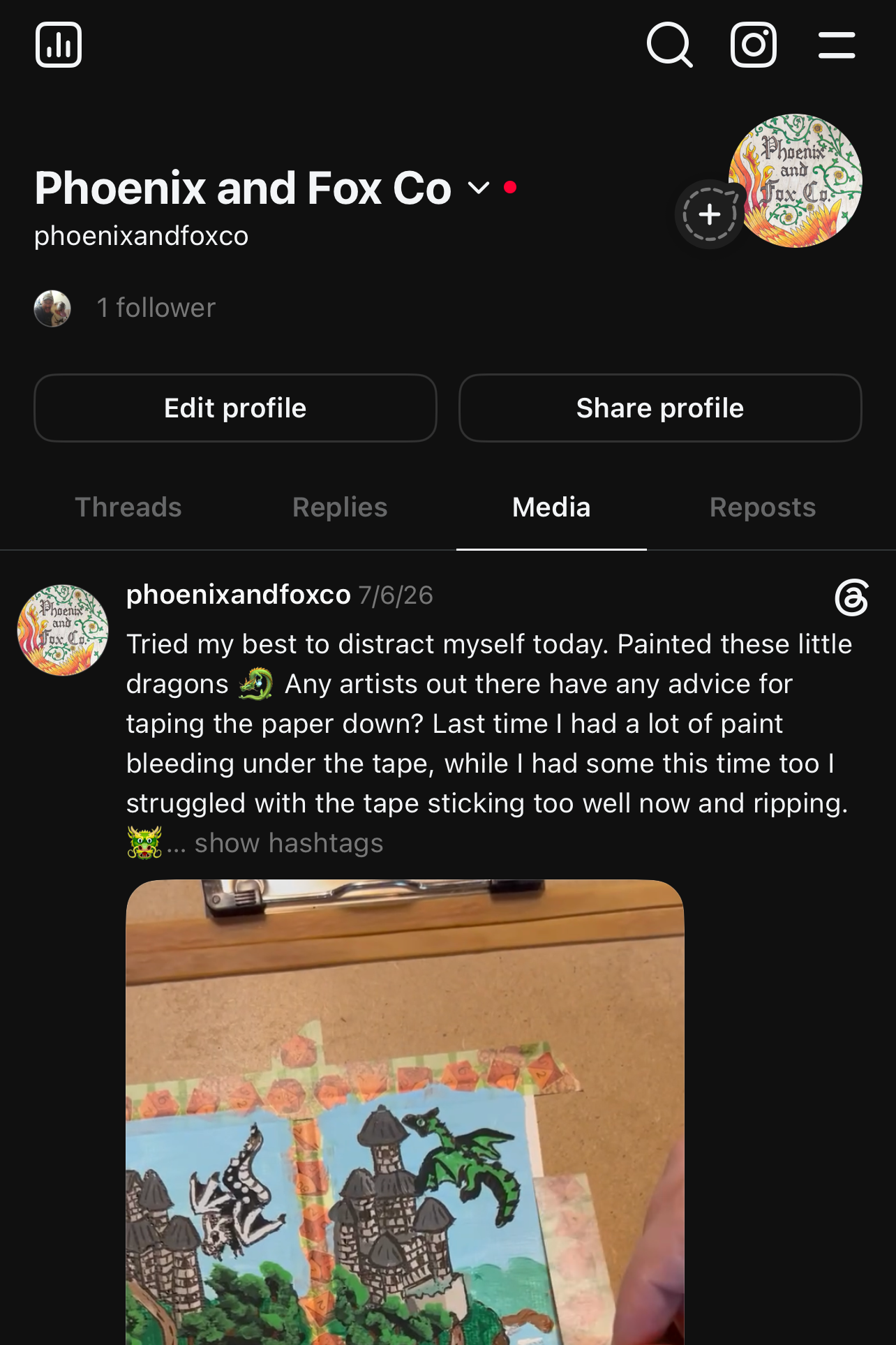 A screenshot of a social media post from Phoenix and Fox Co. showing a hand holding a hand-painted wooden box with green dragon illustrations, set against a dark mobile app interface.